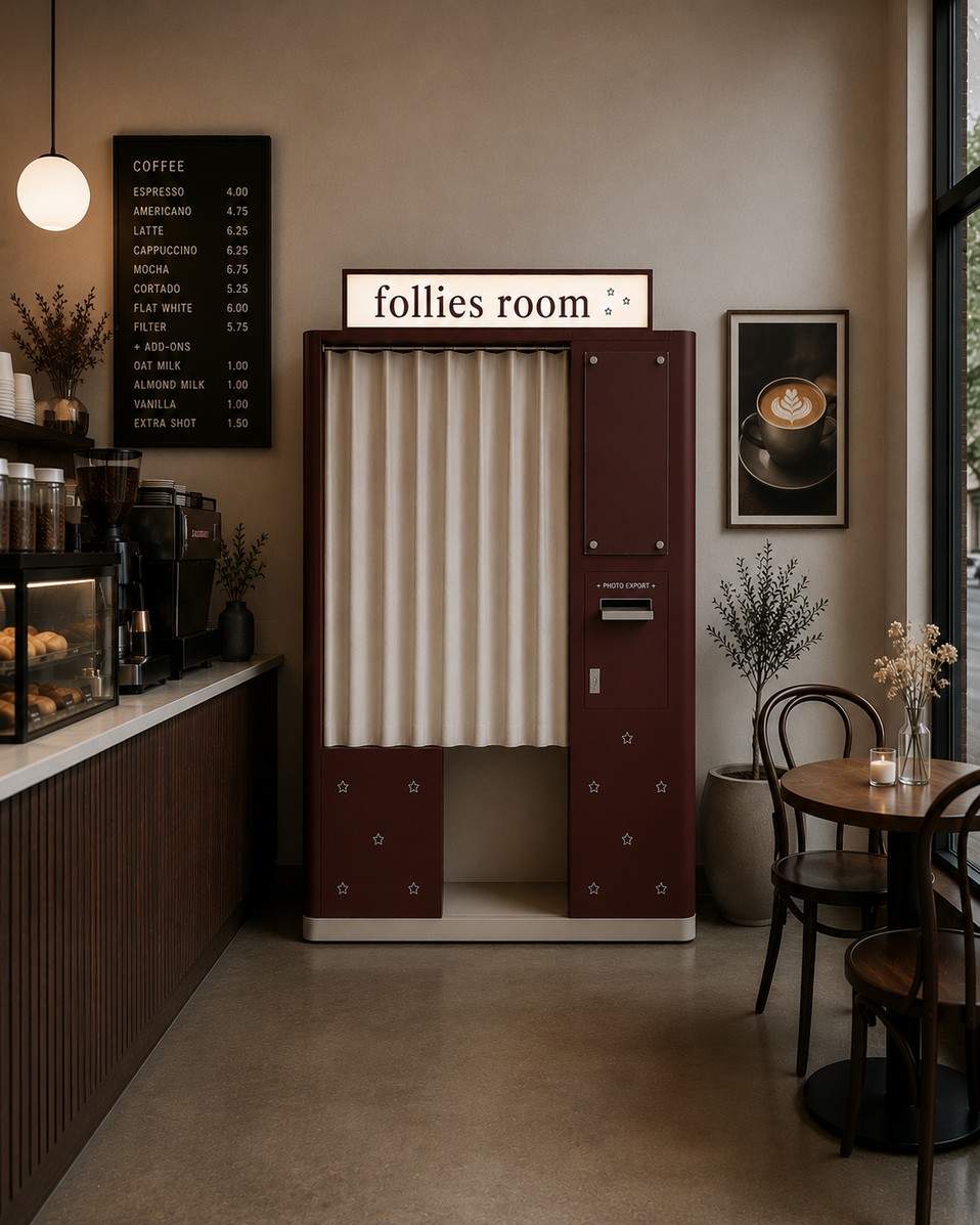 A burgundy Follies Room photo booth installed inside a warm, minimalist cafe